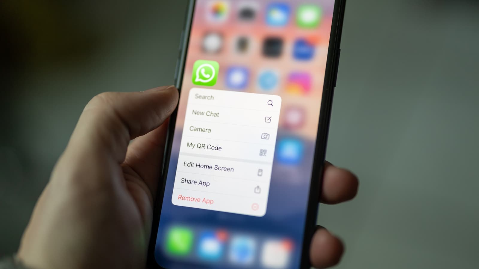 Hand houdt een smartphone vast met het WhatsApp-menu geopend.